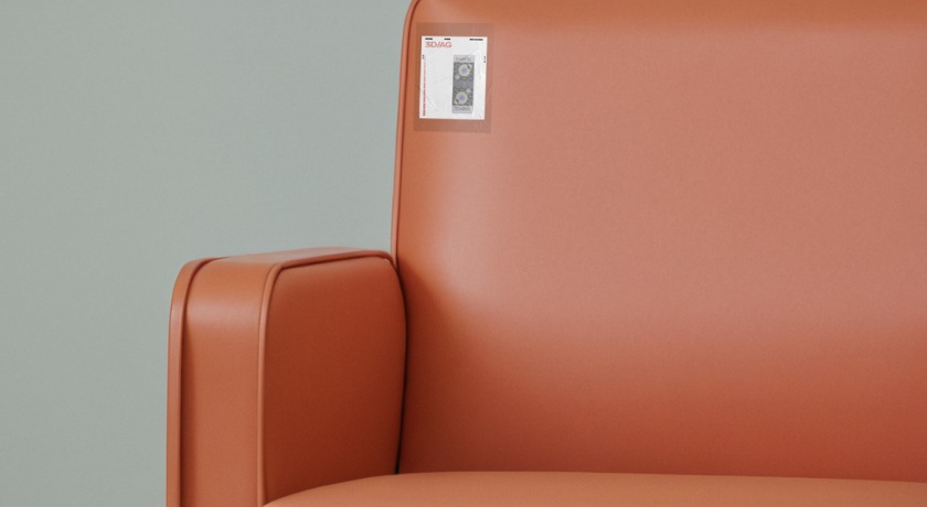Close-up of an orange upholstered chair with a holographic security tag attached